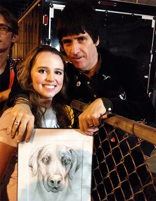 Photo of Artist Chelsea Smith with Guitarist Johnny Marr from the band The Smiths holding an original pet portrait of his pet dog that artist Chelsea Smith created for him.